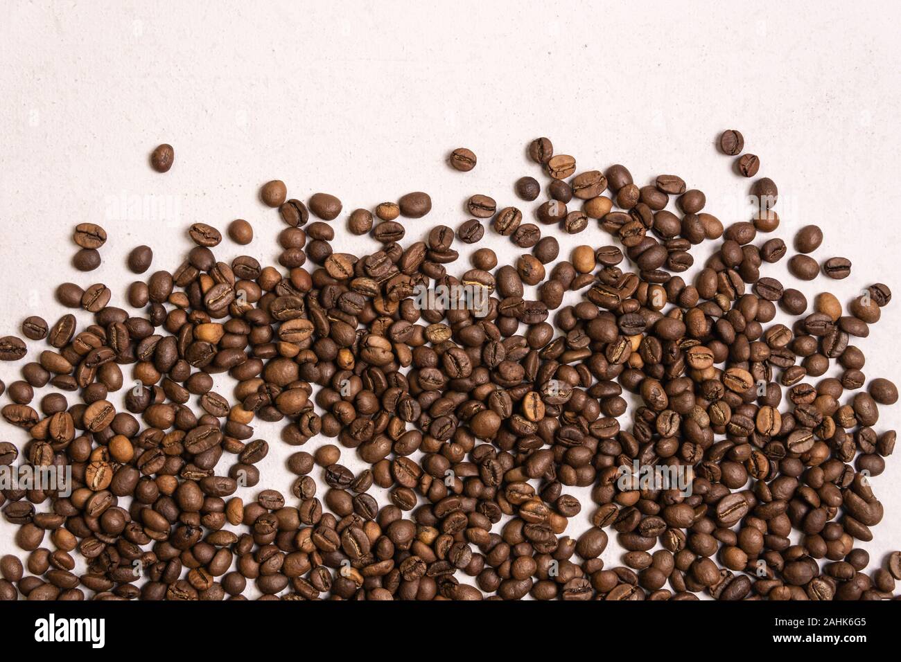 Roasted coffee beans in bulk on a light pink background. dark cofee ...
