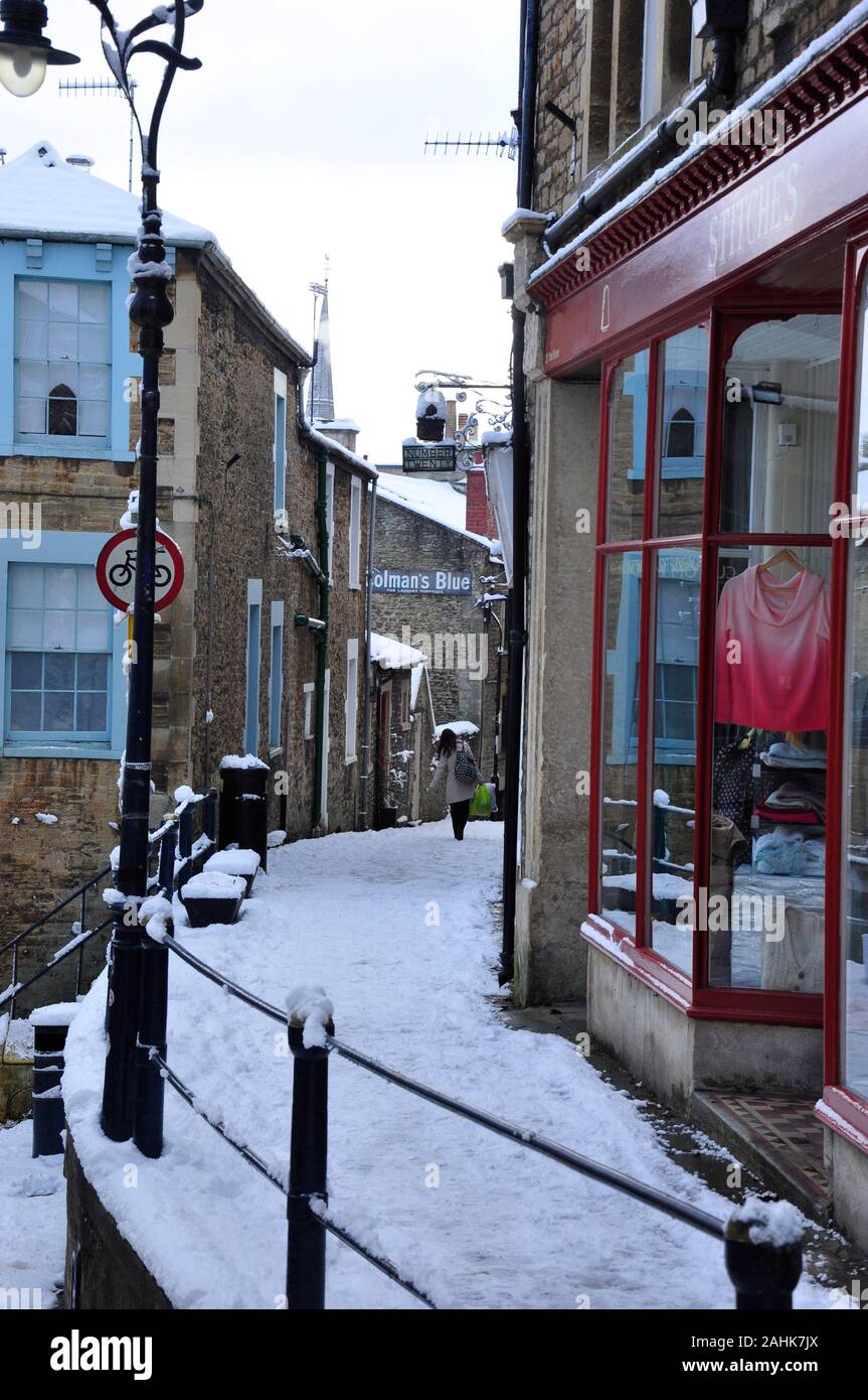 Snow covered Paul street between Catherine Hill and Palmer Street. Few people are walking along this narrow slippery street in Frome ,Somerset. Stock Photo