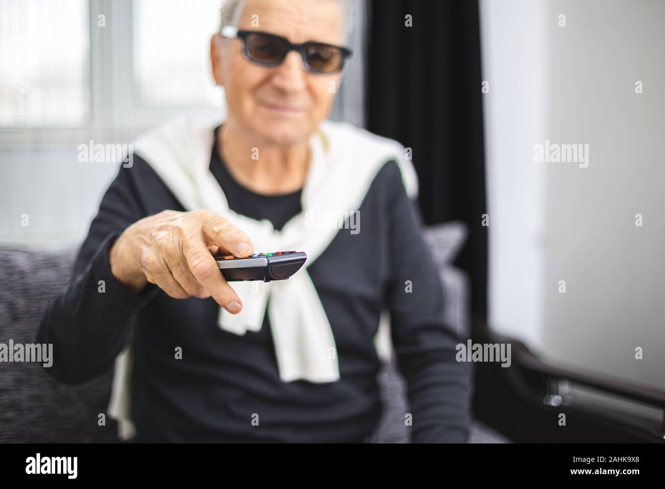 Senior man with 3D glasses and TV remote control in hand Stock Photo