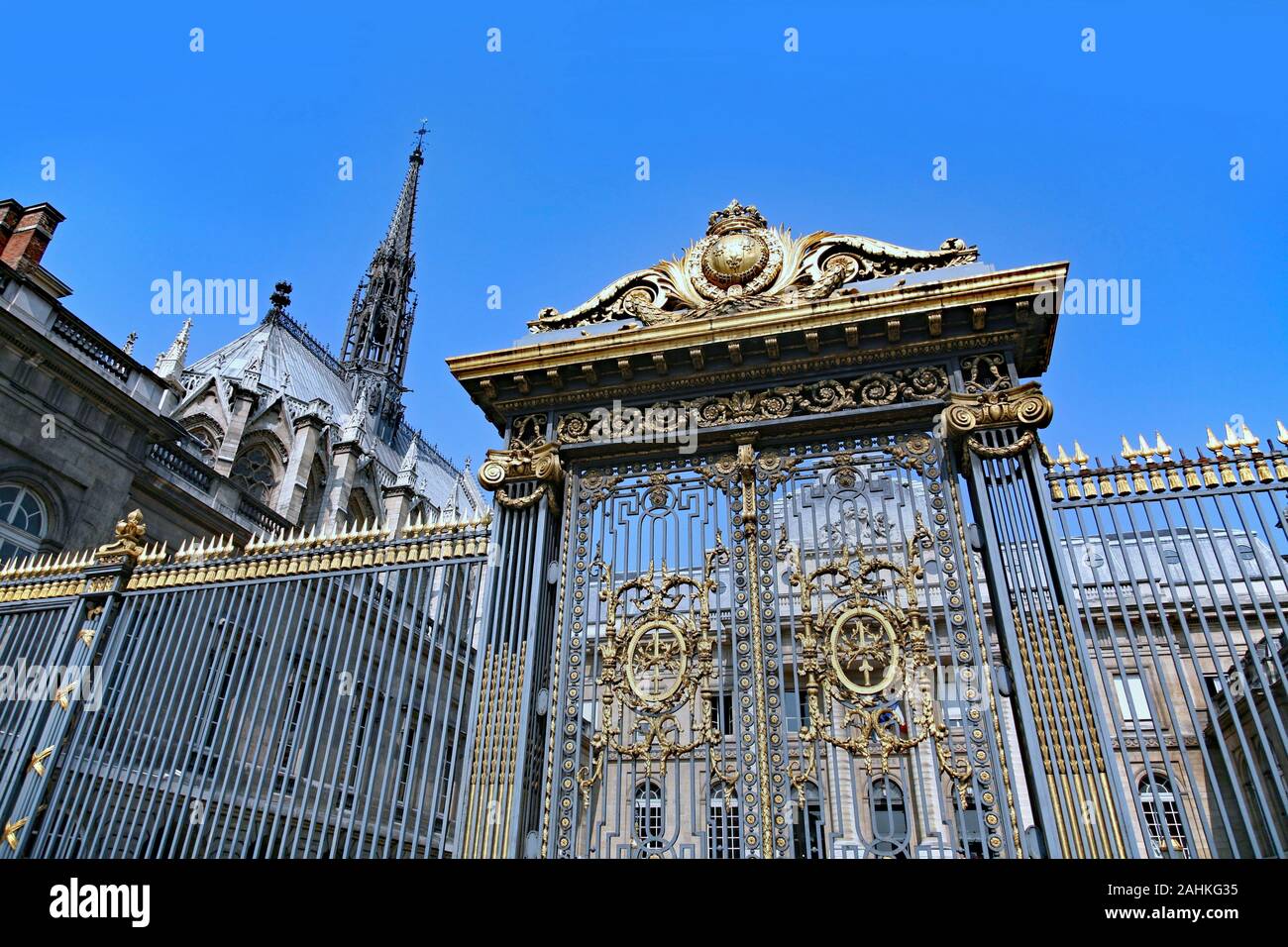 Ornate gilded gate of the Paris Palais de Justice with the steeple of the Sainte-Chapelle in the background Stock Photo