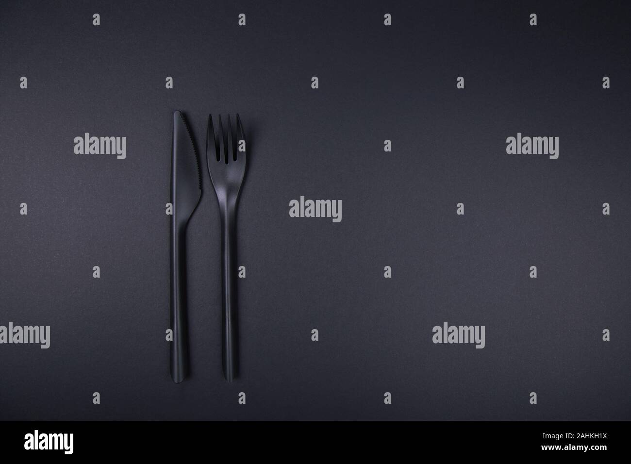 Black plastic fork and knife on black background. Stock Photo
