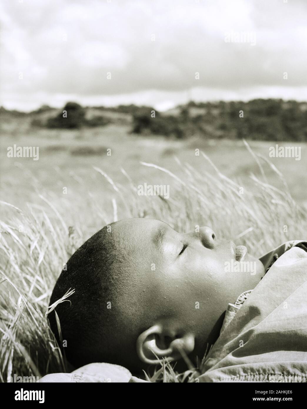 A small boy is sleeping in the grass Stock Photo - Alamy