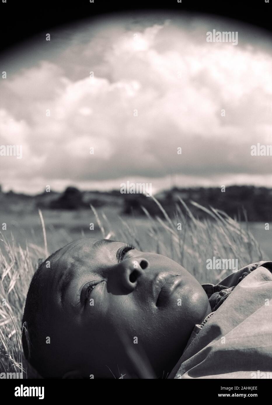 A small boy is lying in the grass. Stock Photo