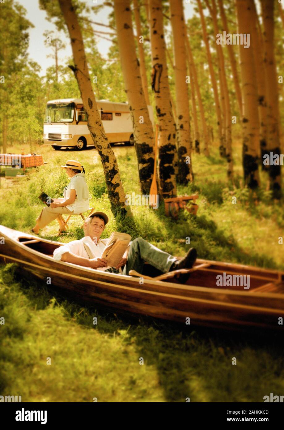 A couple is enjoying reading under a tree. Stock Photo