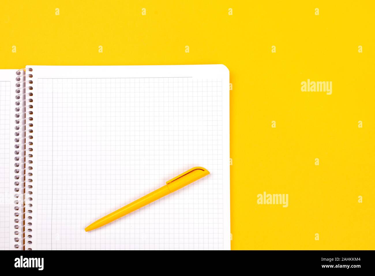 Top view of yellow pen with clean white notebook open with copy space on solid yellow table background for presentation, writer or school education, blogger, novel and friction or brand story concept. Stock Photo