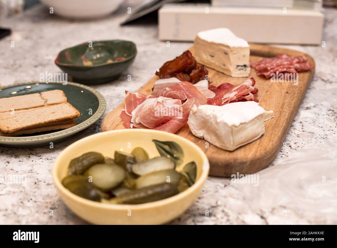 A meat and cheese charcuterie board with crackers and pickles on the