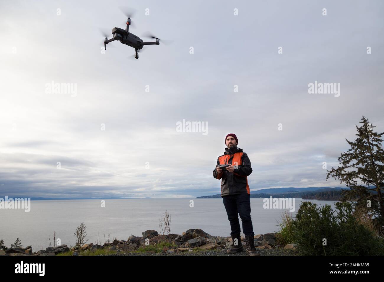 A professional drone pilot flying a drone near the ocean. Stock Photo