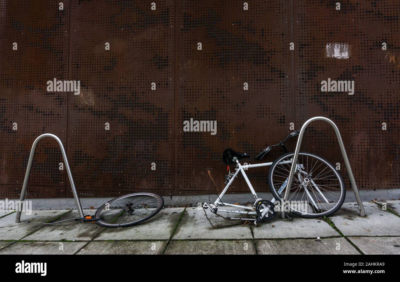A disabled bicycle chained to permanent bike racks in Seattle's University District Stock Photo