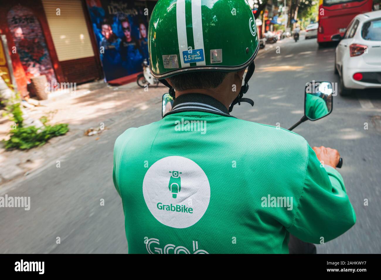 The view from the back of a Grab Bike as the rider navigates traffic in Hanoi, Vietnam, wearing a company branded helmet and shirt Stock Photo