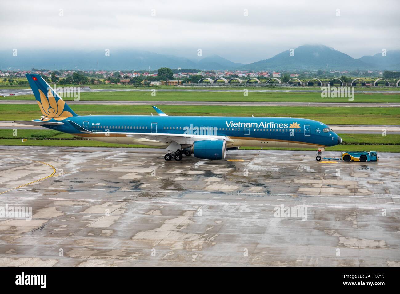 An Airbus A350-900 operated by Vietnam Airlines gets towed by a tug at Noi Bai International Airport, Hanoi, Vietnam Stock Photo