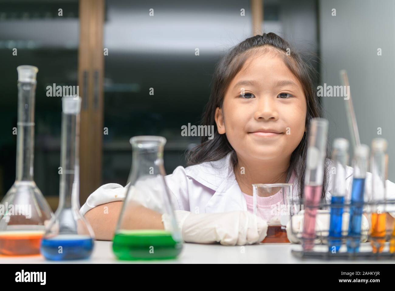 Happy little girl wearing lab coat making experiment in chemical