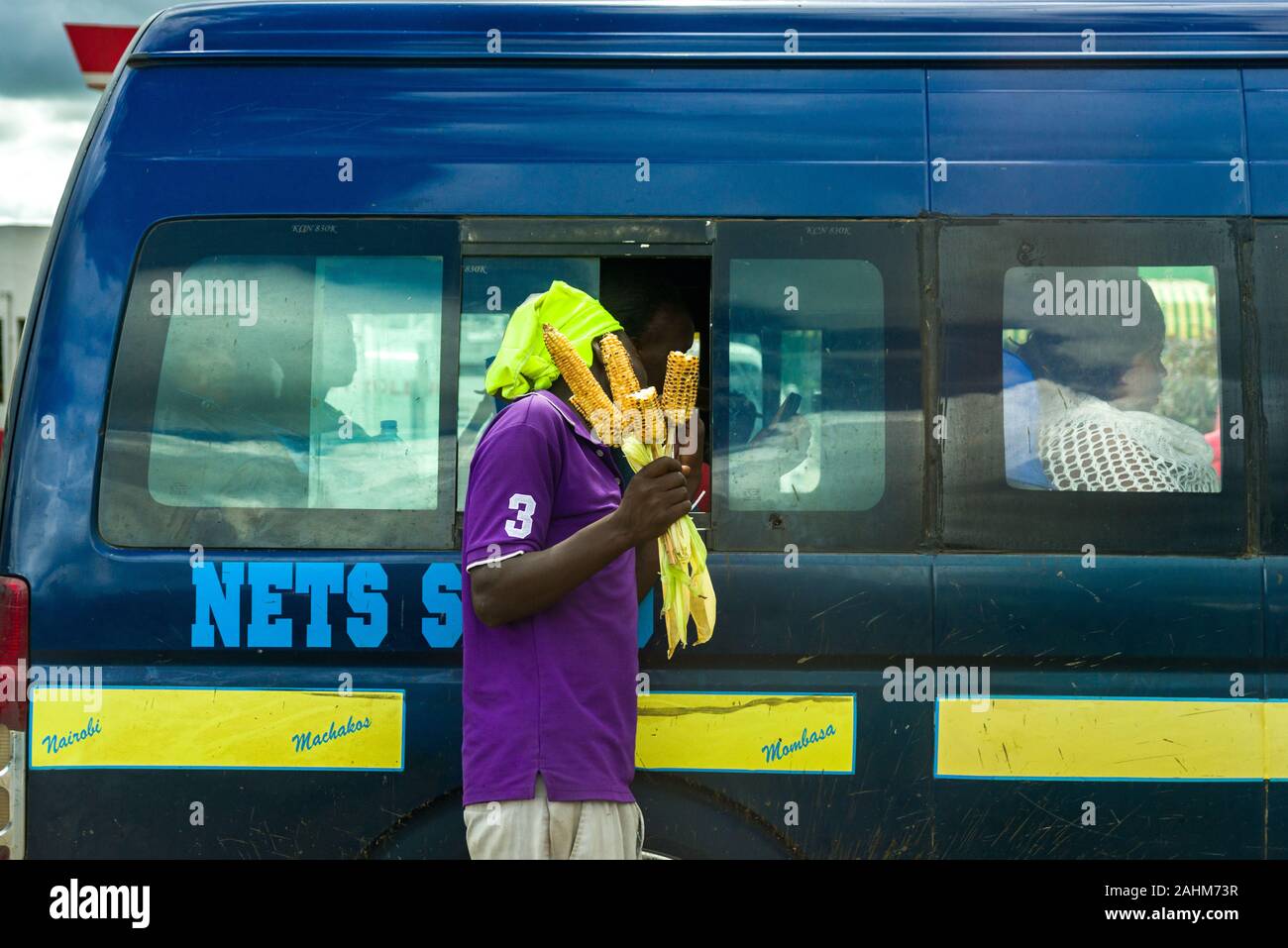 A Kenyan man selling roasted maize to passengers in a matatu bus, Kenya, East Africa Stock Photo