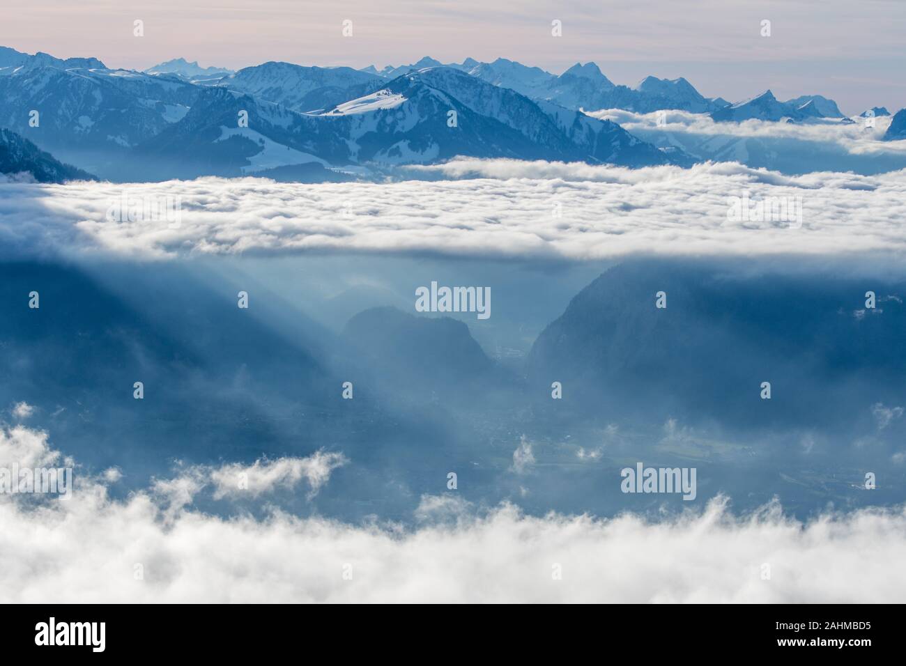 layer of clouds with tyndall effect at the flank of Mount Niesen at the entrance of Simmental Valley Stock Photo
