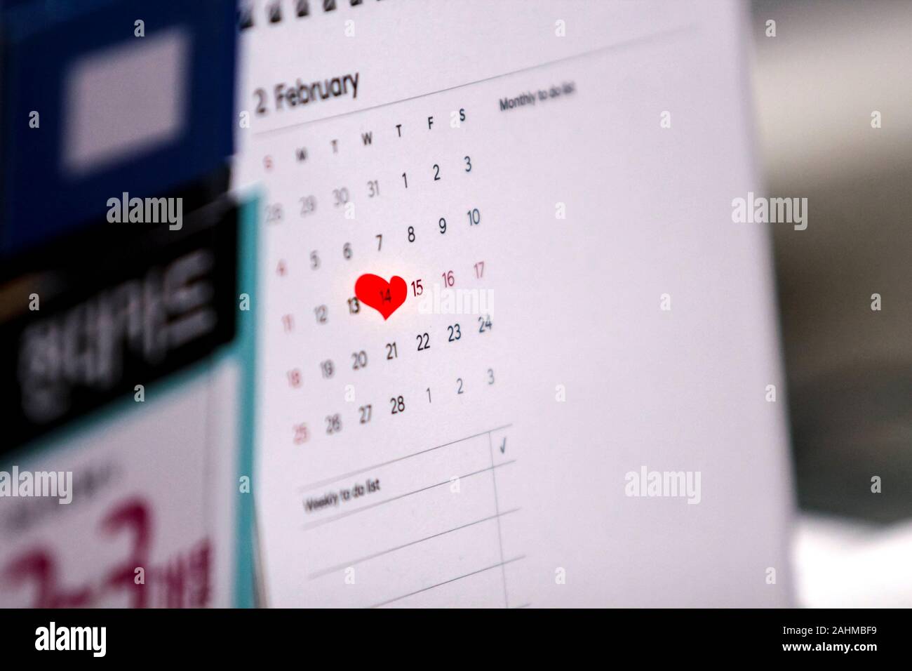 Close up of a desk calendar's February page where Valentine's Day the 14th is marked by an irregular red heart mark. Stock Photo