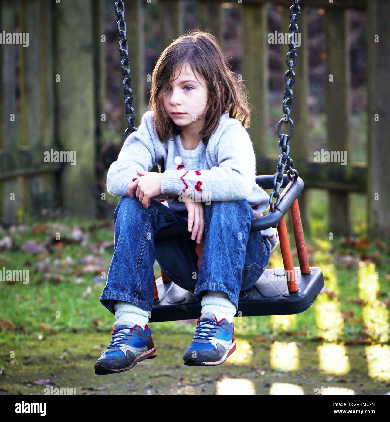 Girl looking thoughtful on a swing in a playground Stock Photo