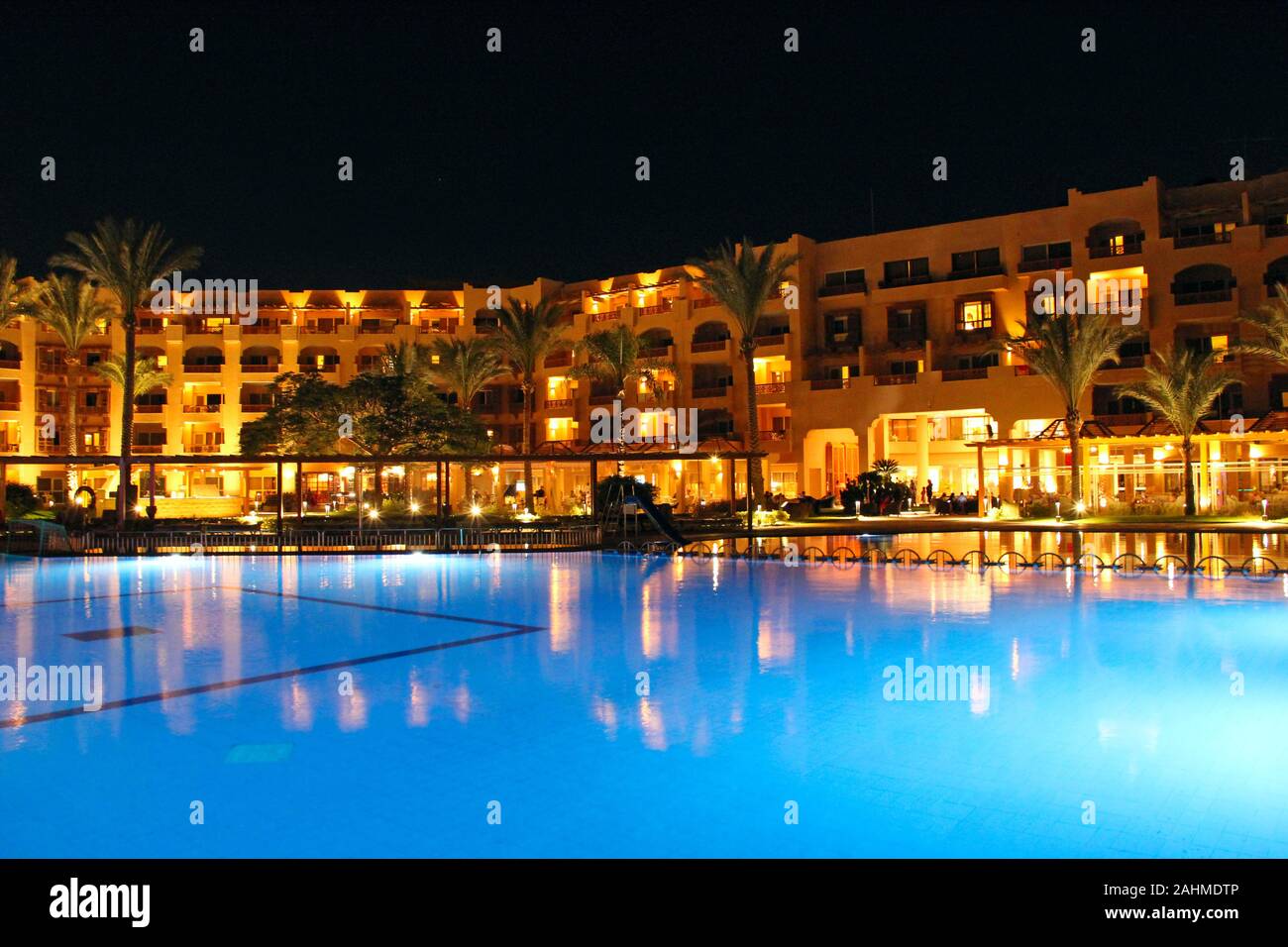 Pool and evening hotel on vacation. People relax by evening near pool.  Lights of evening hotel are reflected in pool water in night. Bright lights  of Stock Photo - Alamy