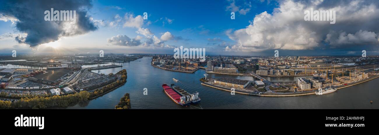 Aerial drone panoramic view of port of Hamburg from above before sunset with dramatic stormy clouds over the sea port Stock Photo