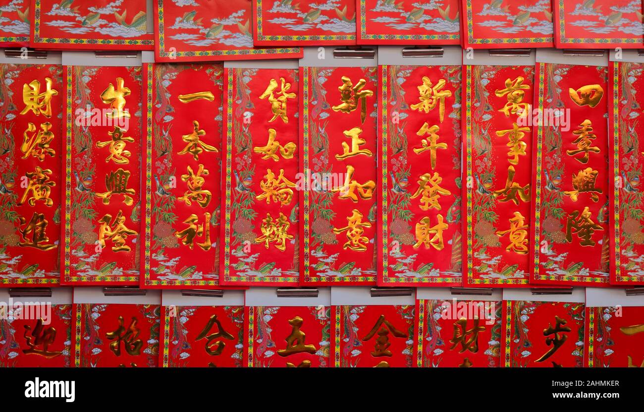 Chinese new year greetings printed with gold color on red paper hanging at a store, the chinese words mean wealth, prosperity and wishes come true Stock Photo