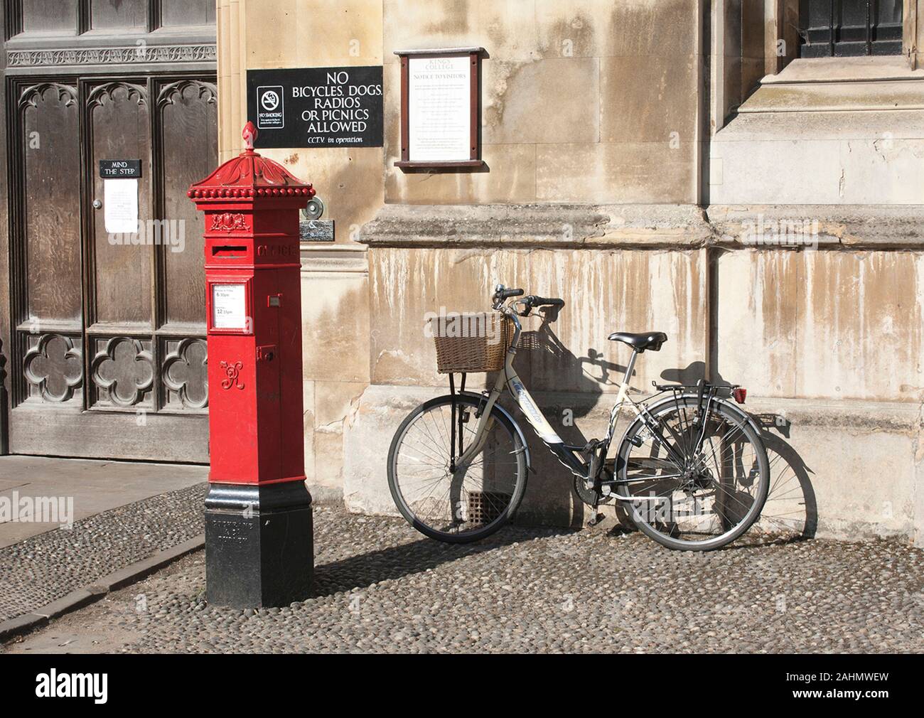 Victorian postbox with bicycle at the entrance to Kings College in Cambridge. Stock Photo