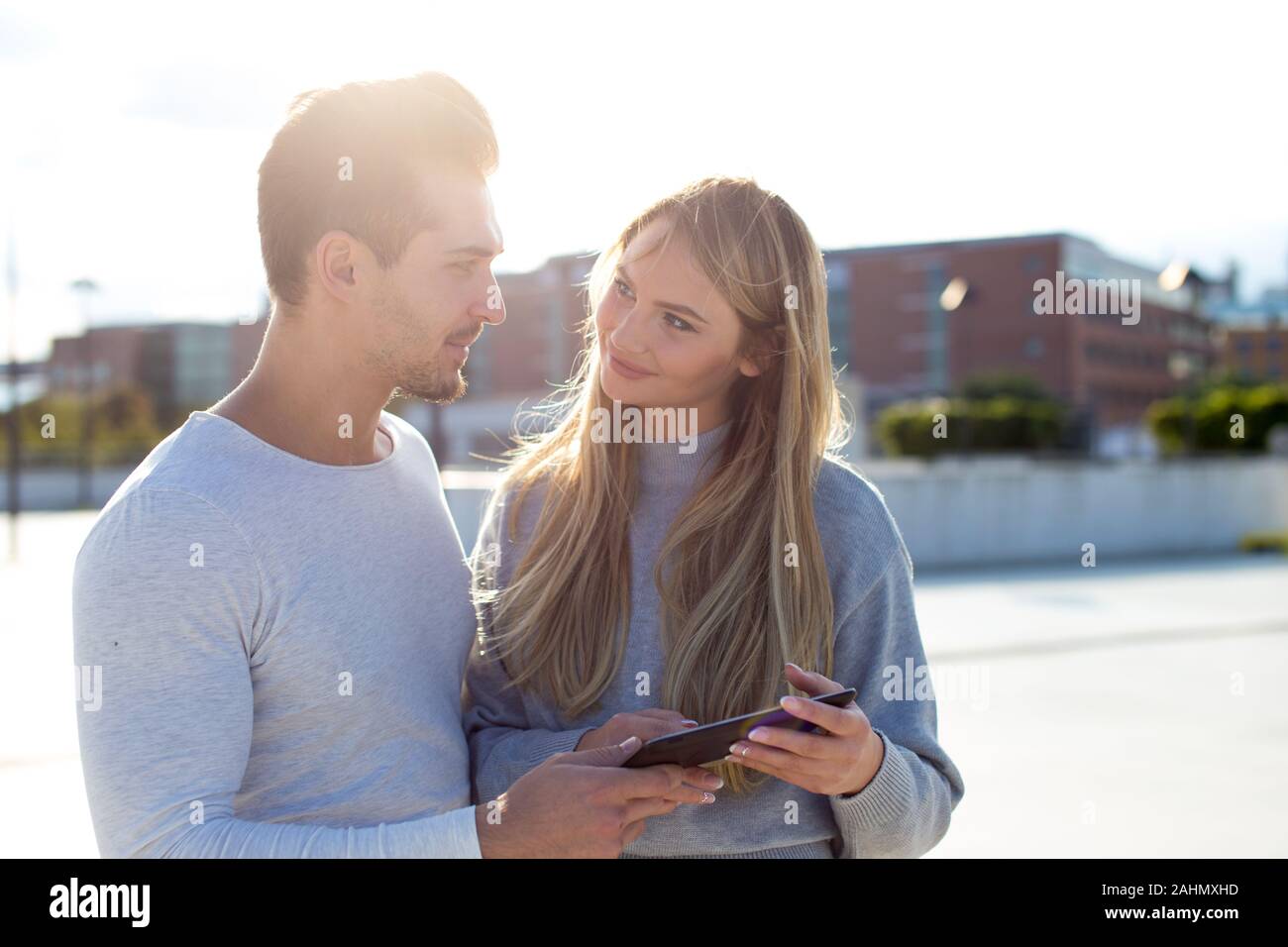 Young urban caucasian couple with digital tablet looking each other outdoors Stock Photo