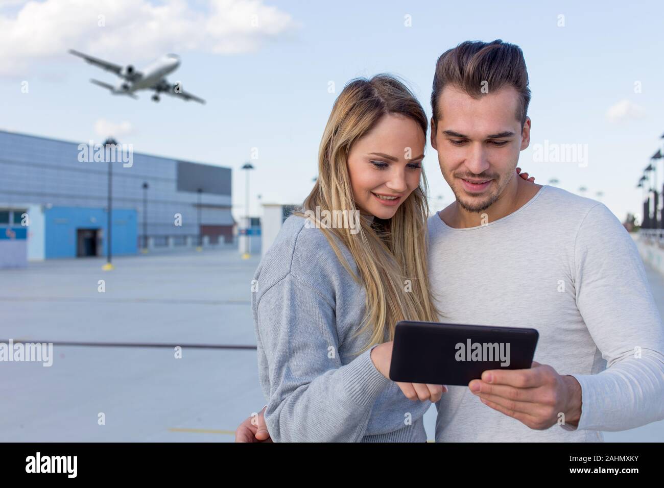 Young caucasian couple ordering air ticket by app on digital tablet outdoors Stock Photo