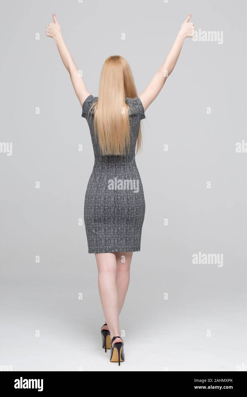 Blonde woman in formal wear arms raised and thumbs up full body Stock Photo