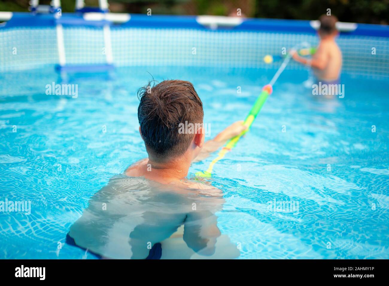 Little boys playing with water cannon in swimming pool at summer Stock Photo