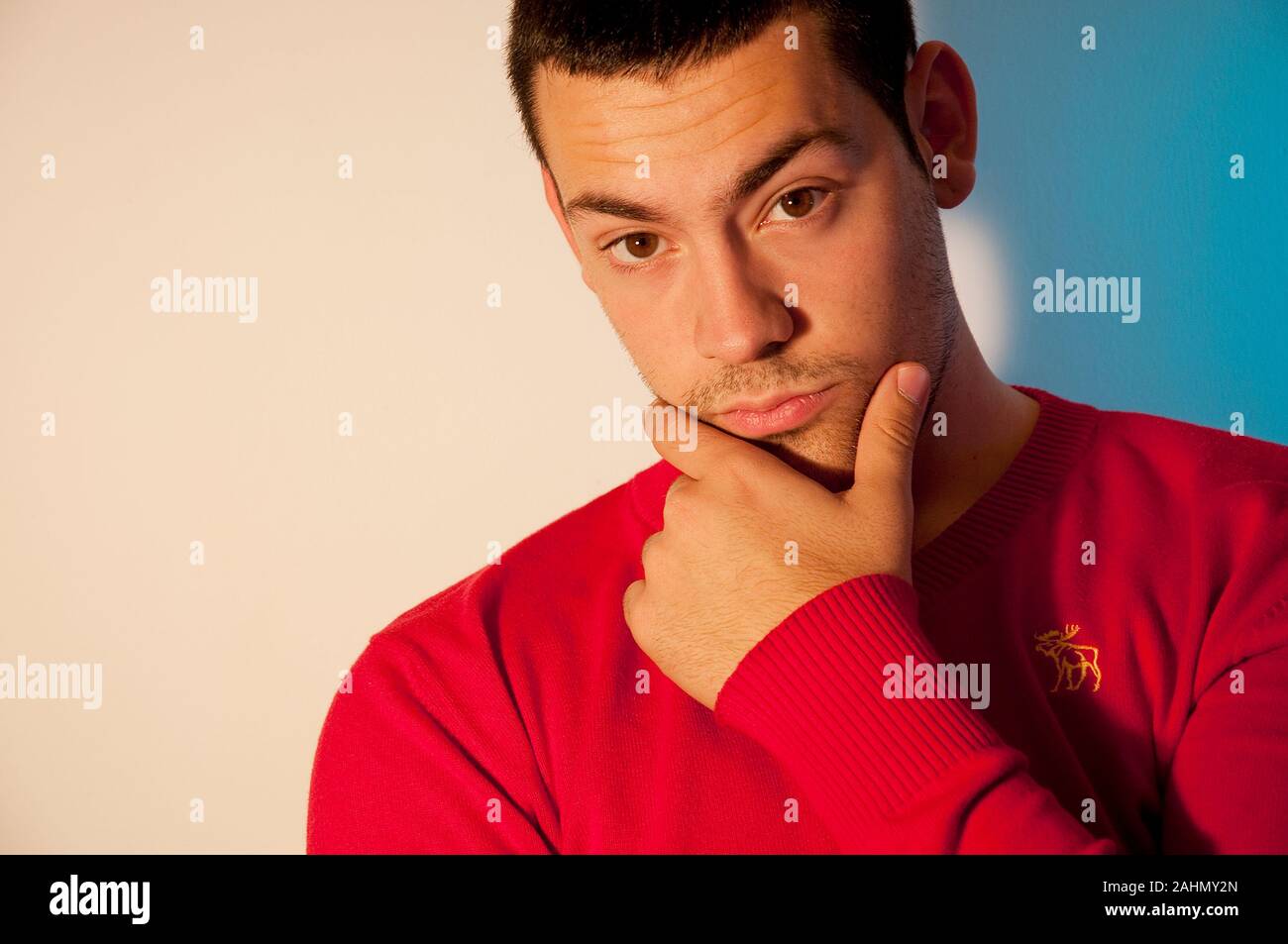 Young man, hand on chin, looking camera. Close view. Stock Photo