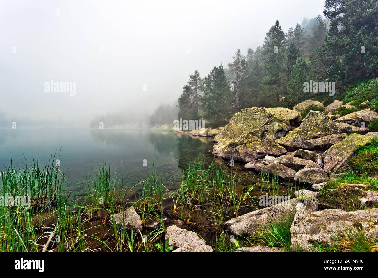 Scene of Laquette high mountain lake border in Neouvielle nature reserve of French Pyrenees, the rocky water border at foreground, the water surface a Stock Photo