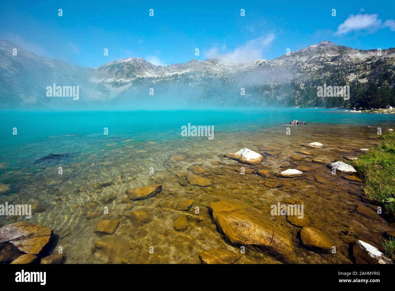 Mystery colors of Aubert lake in Neouvielle Natural reserve, Transparent water at foreground, the mist at lake surface gives extraordinary cyan nuance Stock Photo