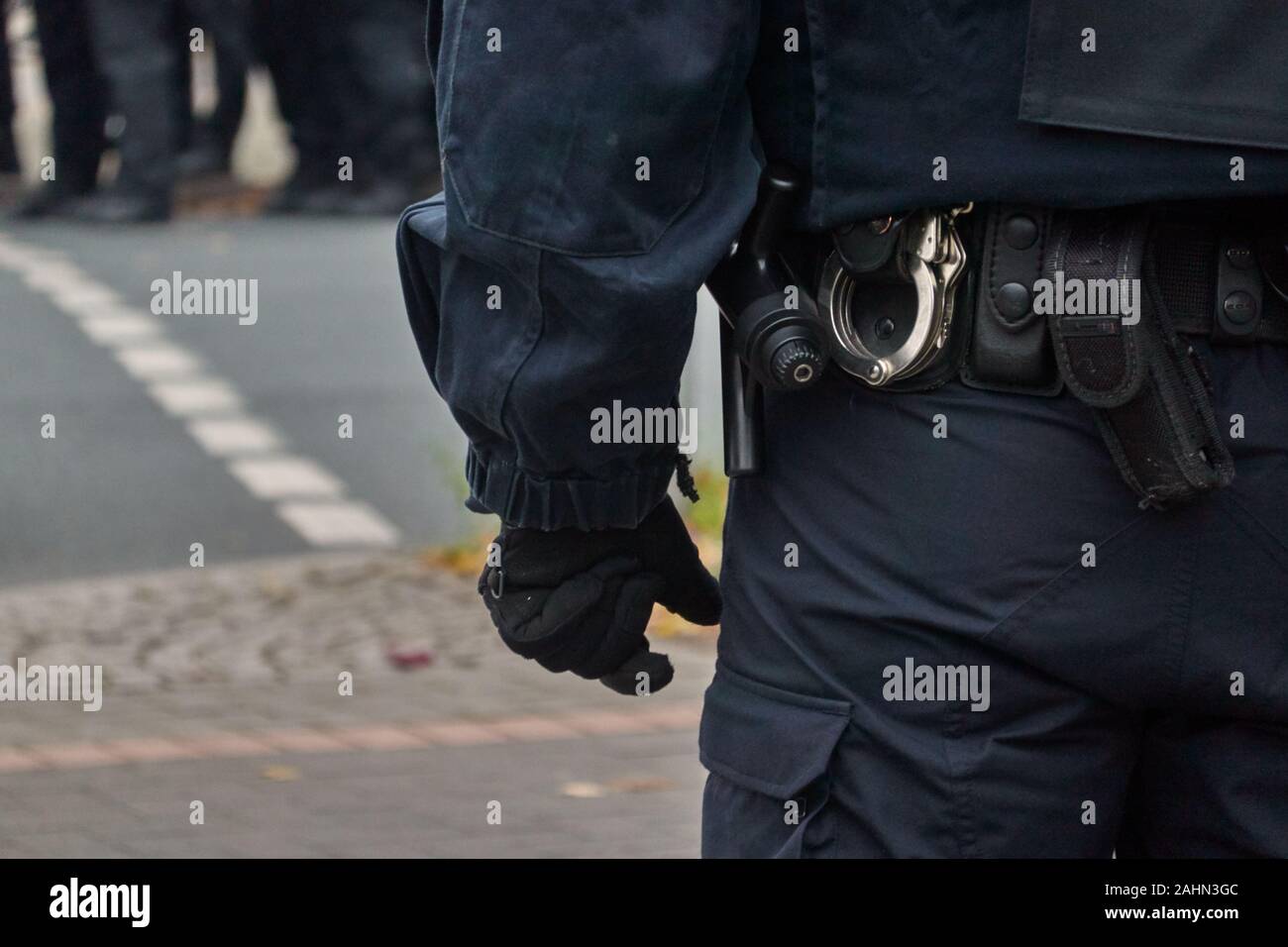 Belt of a policeman in black uniform in action, with handcuffs, baton and belt bag. Stock Photo