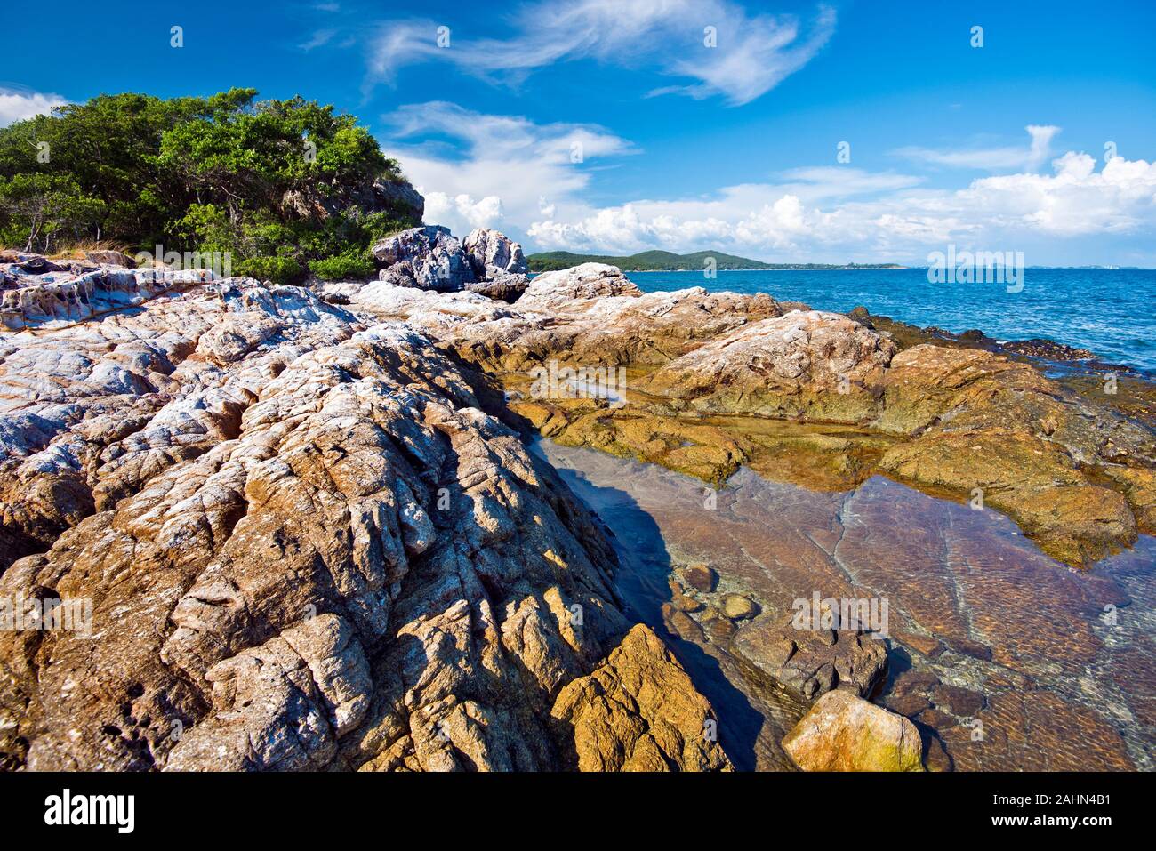 Southern Coastline wild landscape in Ko Samet island, textured stones of the coast are at foreground, Thailand Stock Photo
