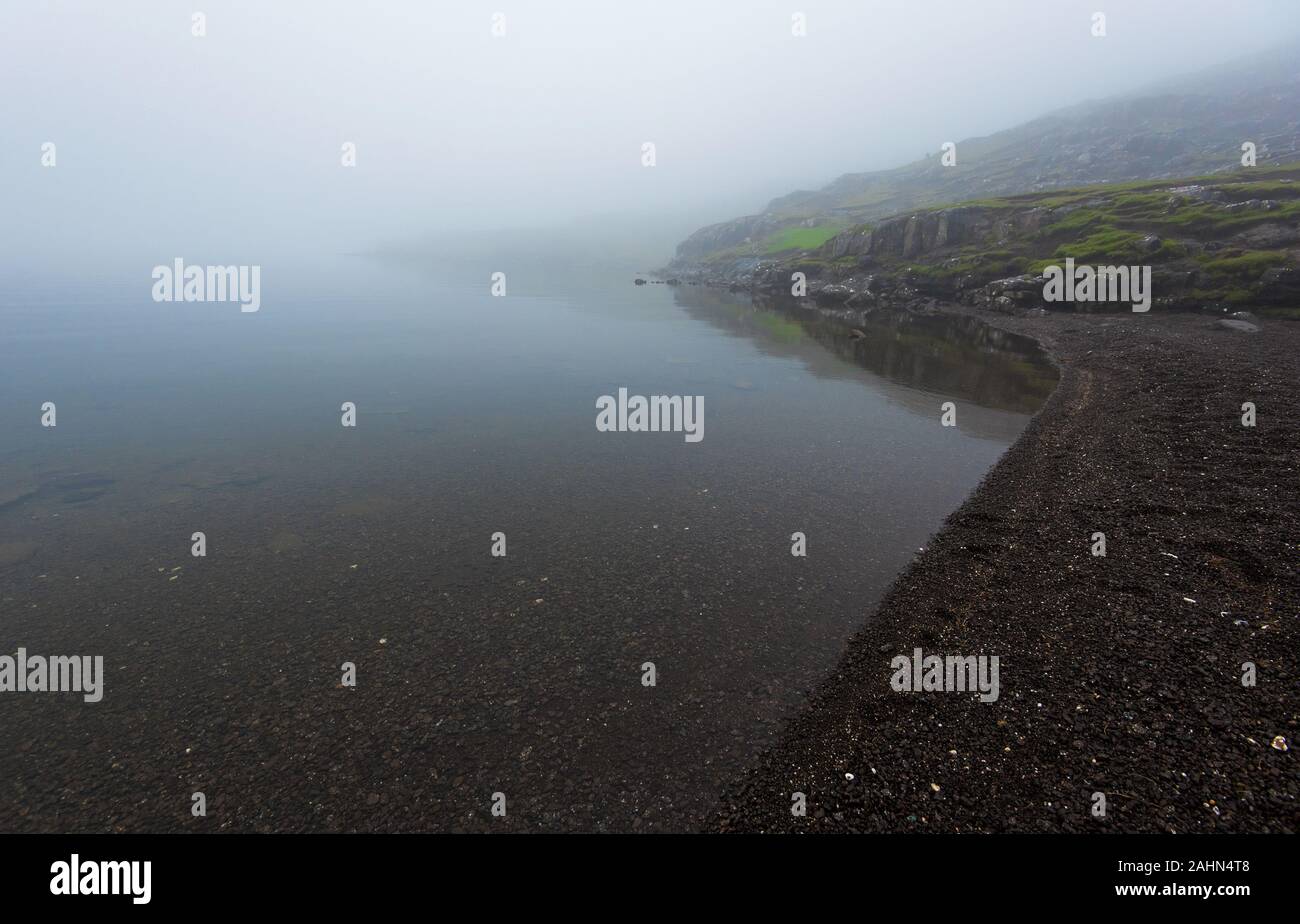 Misty landscape of the gravel beach of Sorvagsvatn Lake in  Faroese island of Vagar Stock Photo