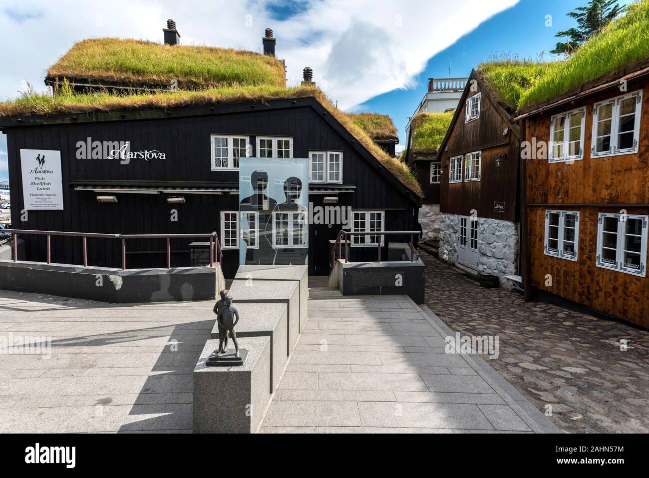 Torshavn, Faroe – July 11, 2018  Aarvegur Street view in harbor quartiers of Torshavn city, modern sculptures in the middle of the old traditional bui Stock Photo