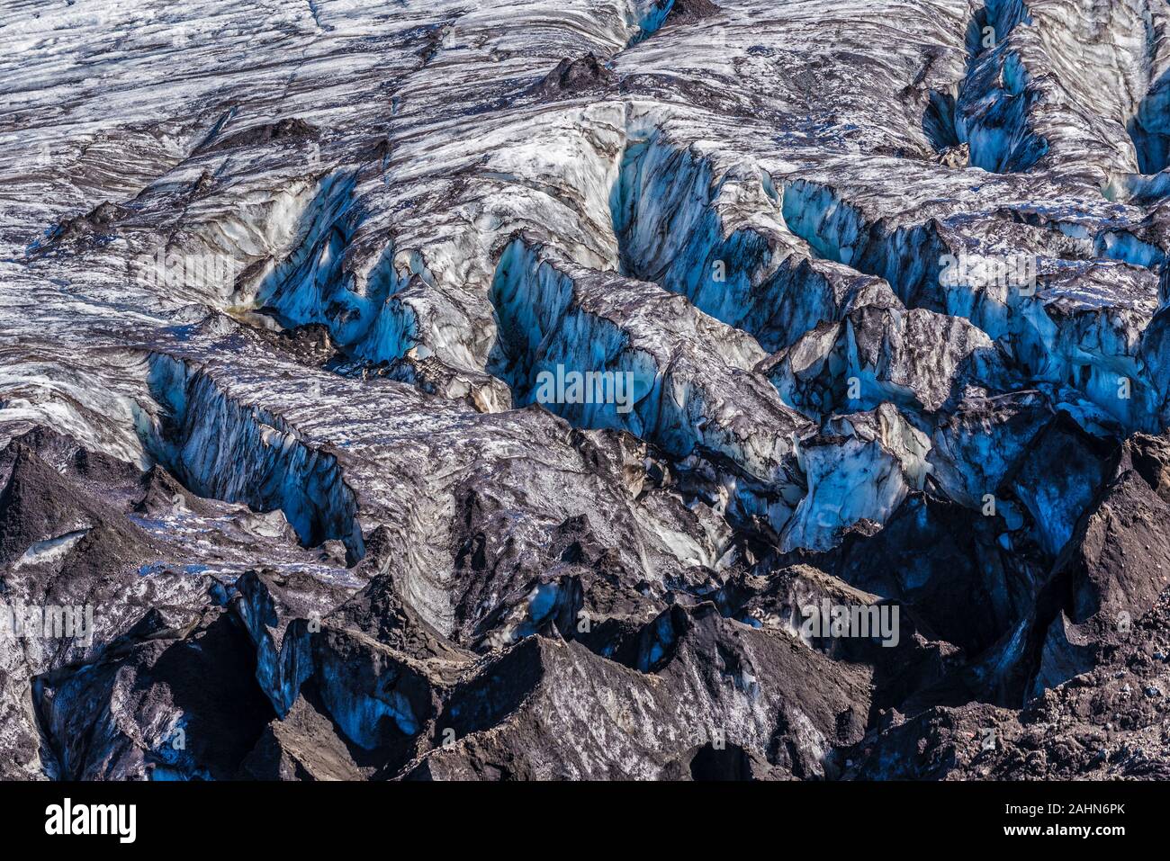 Cracked glacier surface with deposits of black volcanic cinder, cyan blue icy reflects are at interior walls of cracks, Glacier of Kverkfjoll massif i Stock Photo