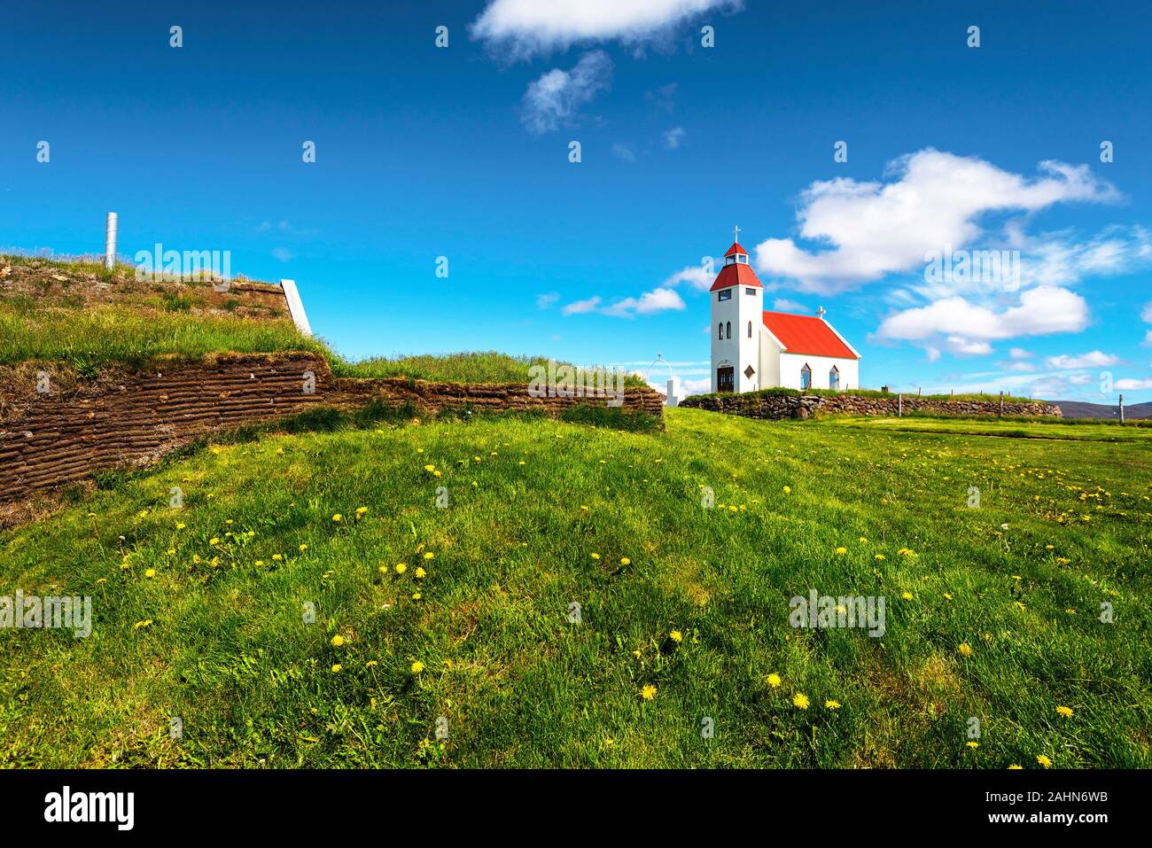 View at the church of Modrudalur settlement in Eastern Island, green grassland and the wall of traditional islandic turf construction are at foregroun Stock Photo