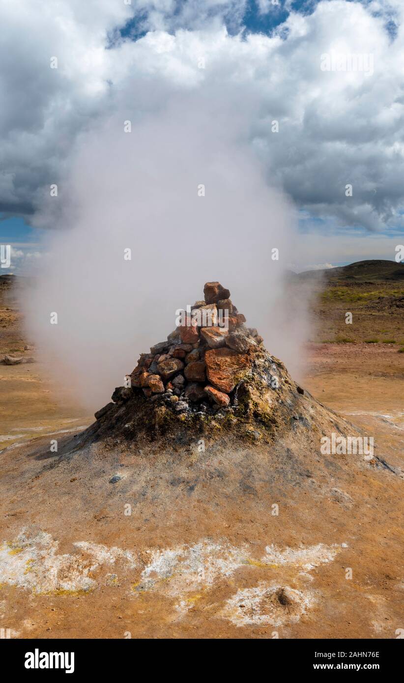 Fumarole engaging vapor and smoke in Hverarond hydrothermal site in Northern Island. Cloudy sky is at background Stock Photo