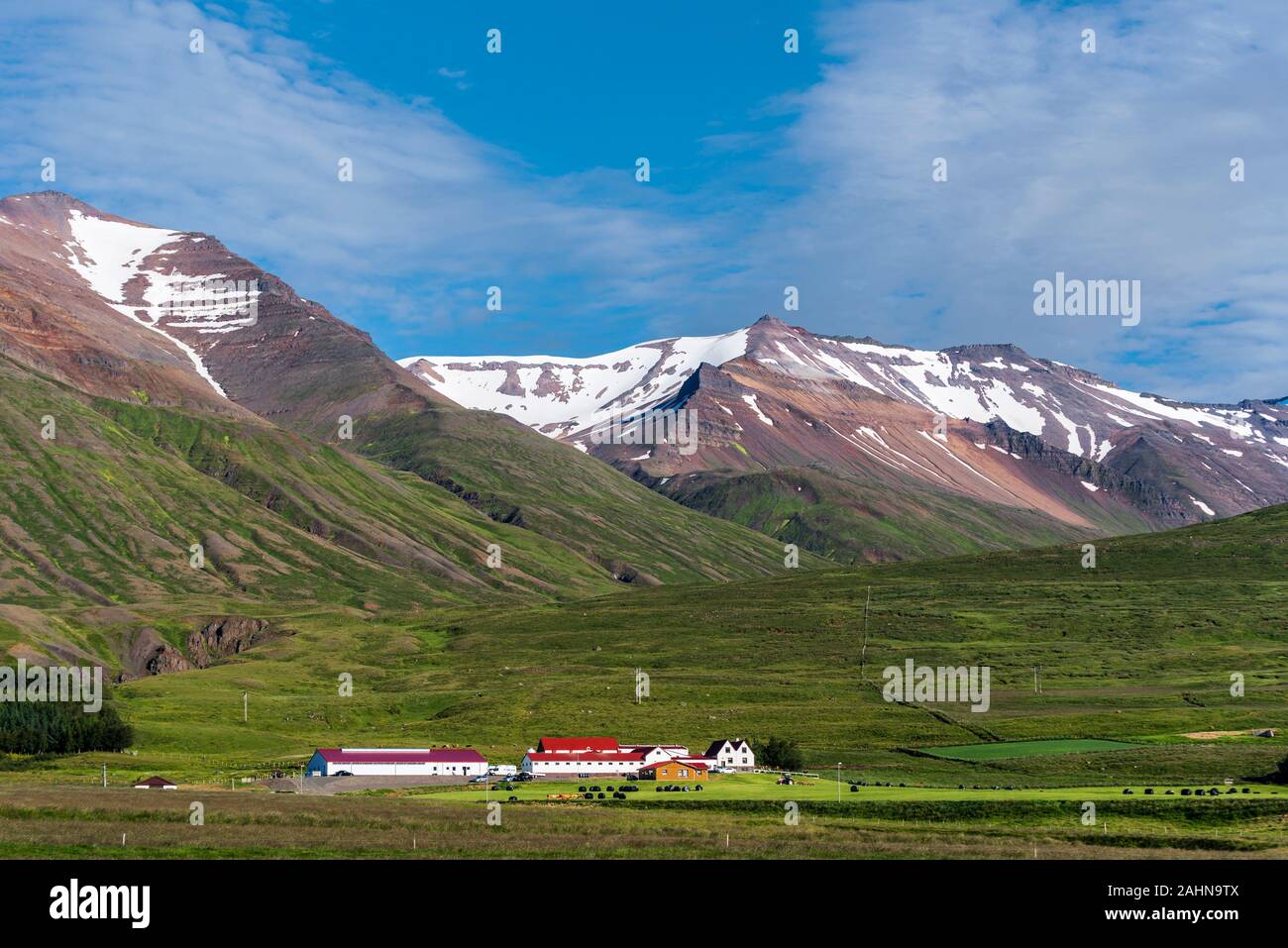 Typical Icelandic farm in the green valley underneath snowy mountains in Northern of Iceland. Horgarsveit municipality of North-central Iceland. Stock Photo