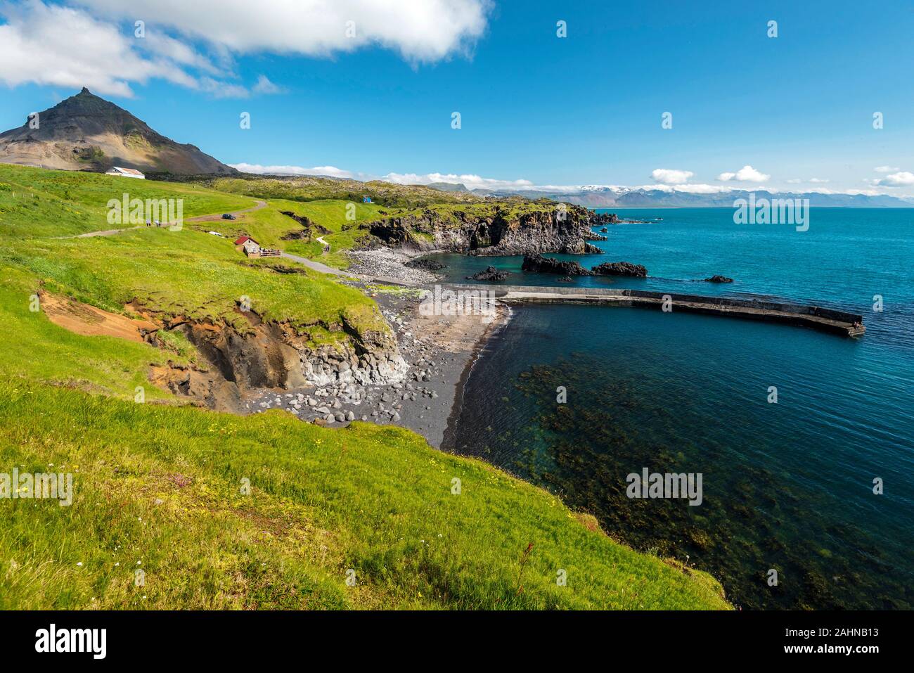 View at Hellnar and Valasnos cliffs on Snaefellsnes peninsula in Western Iceland. Basalt rocks and concrete pier and islets are washed by blue Ocean w Stock Photo