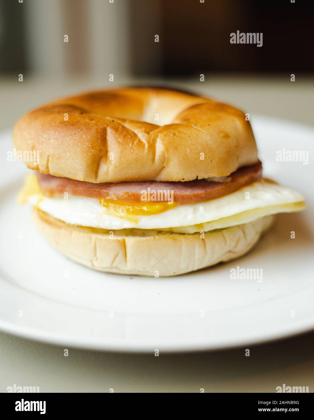 Canadian bacon egg bagel breakfast sandwich close up with blurry ...