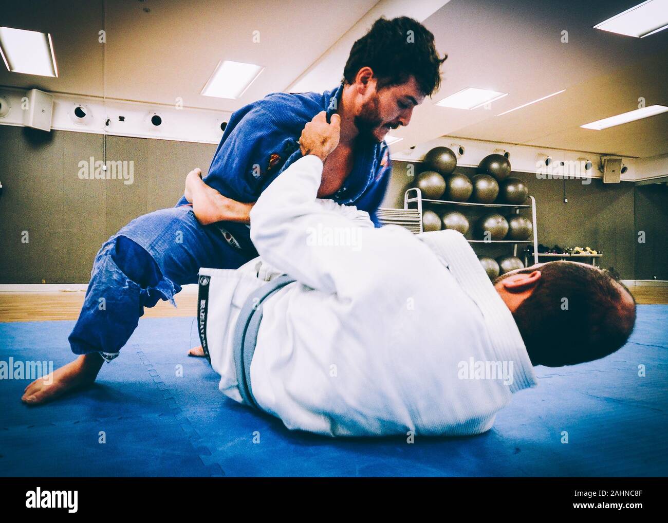 Two young men practice Brazilian Jiu-Jitsu sparring, a grappling type martial arts with a kimono gi - NOT STAGED Stock Photo