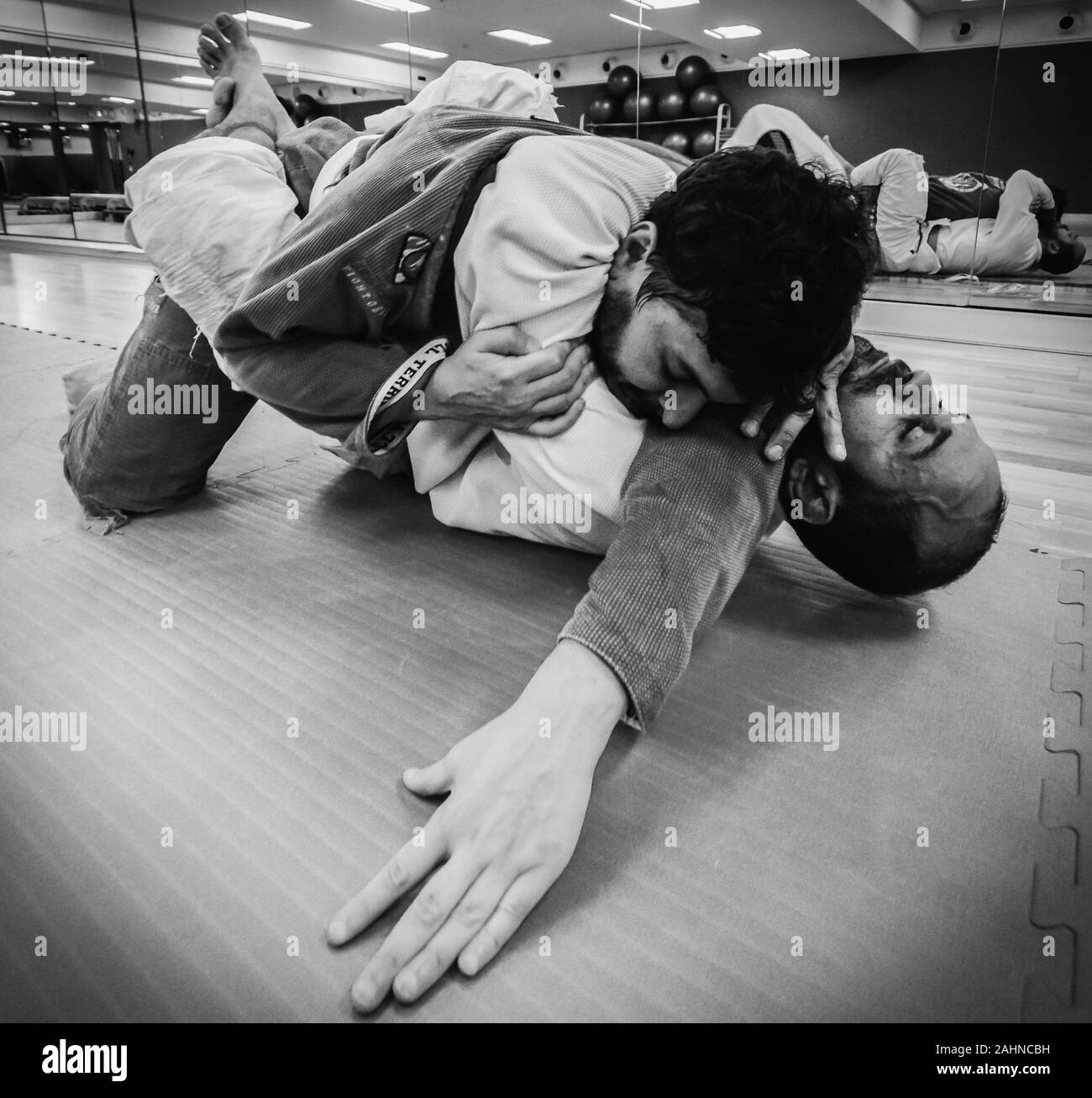 Two young men practice Brazilian Jiu-Jitsu sparring, a grappling type martial arts with a kimono gi - NOT STAGED Stock Photo