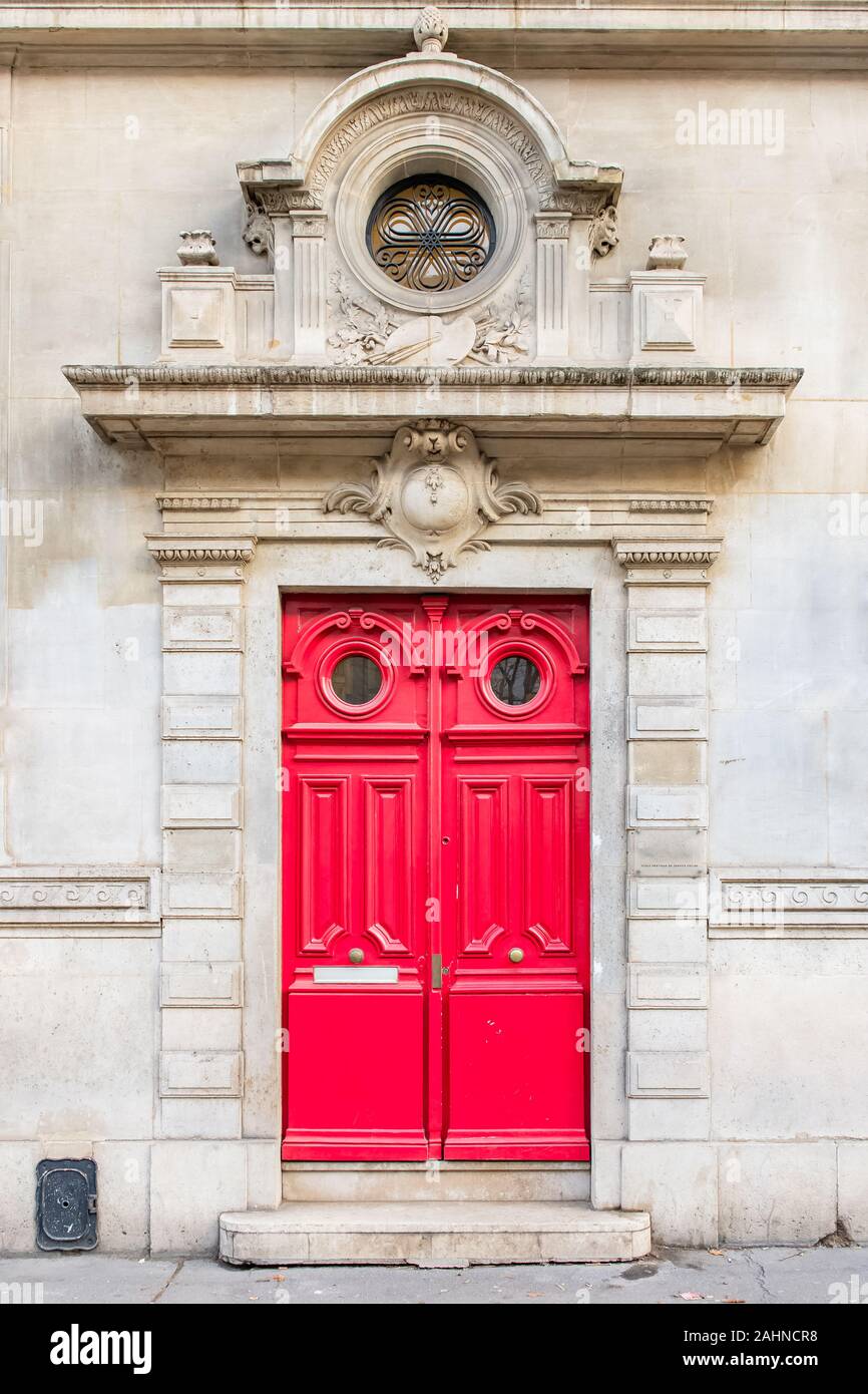 Paris, beautiful red wooden door, typical building in the Marais, with carved lintel Stock Photo