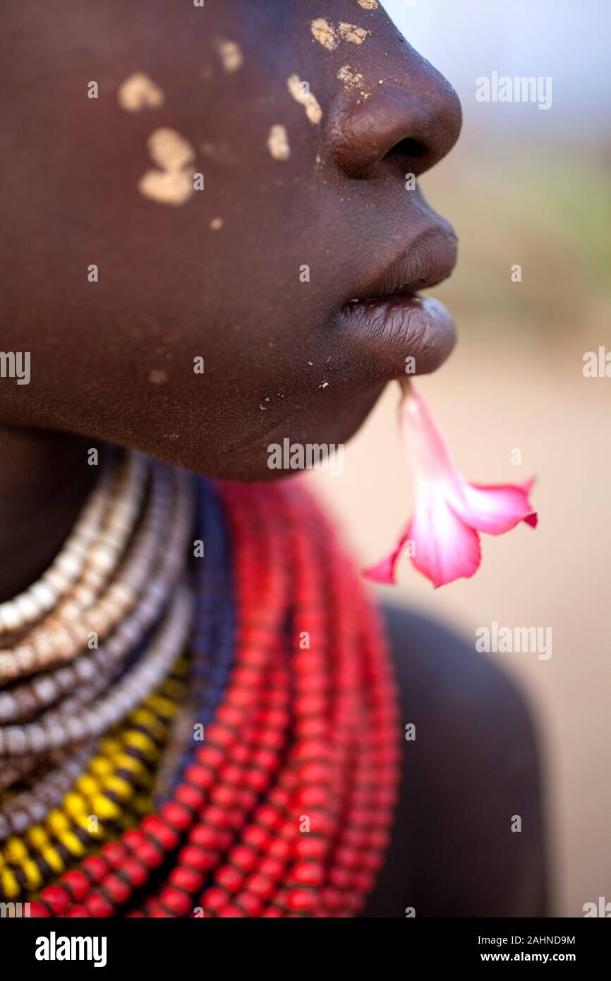 Girl from Karo tribe with flower near her lips and painted cheeks, Omo valley, Ethiopia, Africa Stock Photo