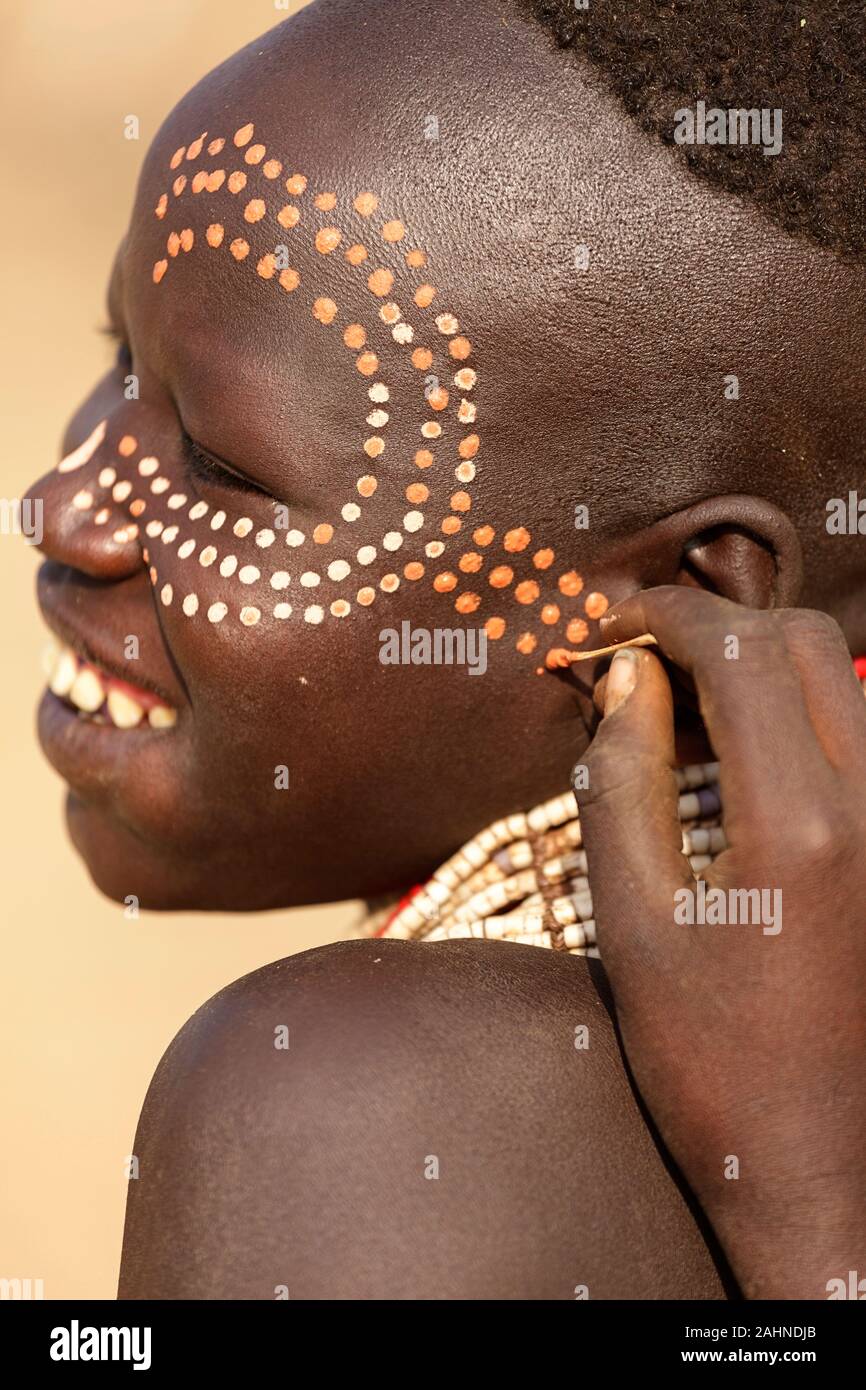 Young women from the Karo tribe painting each other face with traditional pattern, Omo valley, Ethiopia, Africa Stock Photo