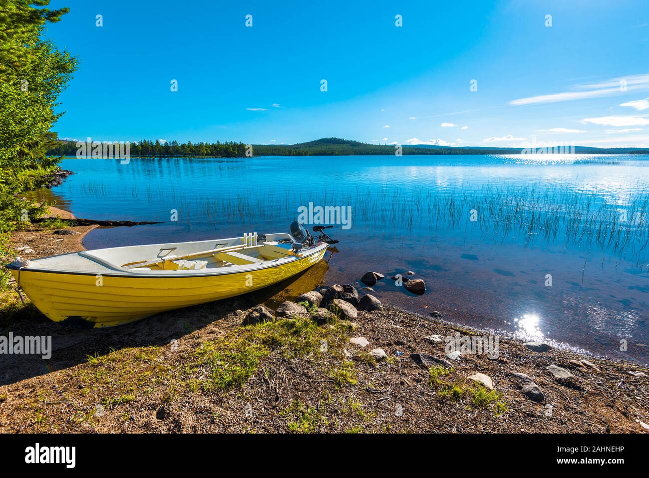 The motor boat in the border of Siebdniesjavrrie lake Swedish Lapland. The sun is reflecting in the water. Vasterbotten county, Norrland, Sweden. Stock Photo