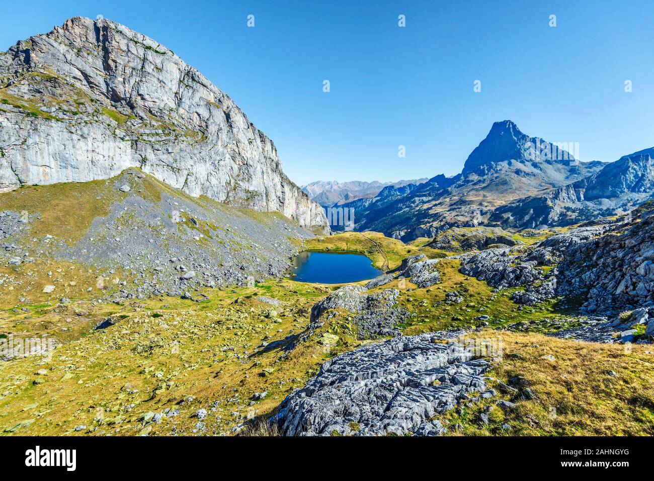 View at Casterau Mountain at left and Casterau lake in French Atlantic Pyrenees, as seen in October.  Ossau peak  is at background. Stock Photo