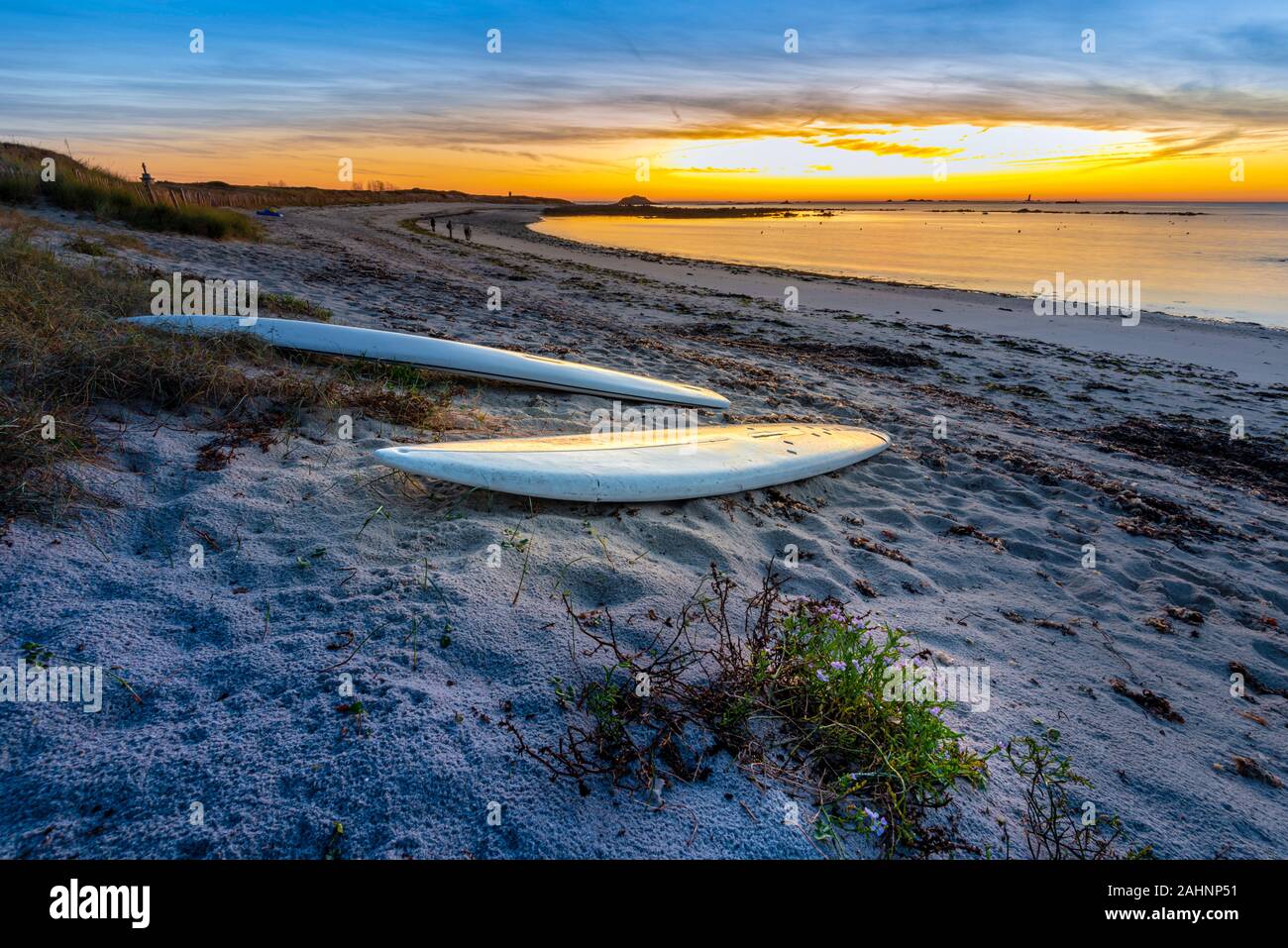 The sunrise in the beach in South of Hoedic Island in French Brittany, La Croix Port. Abandoned windsurfing boards are at foreground. Stock Photo