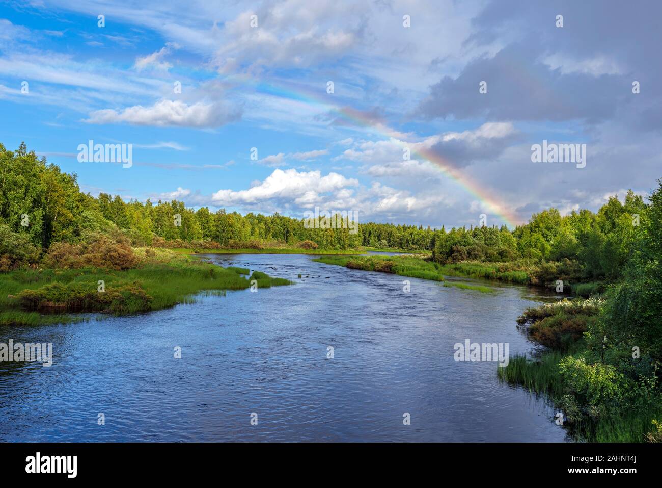 The flow of Kasmanjoki river bordered by pin forests in Finnish Lapland. The sky with rainbow is at background. Picture is taken from E63 Kuusamo road Stock Photo
