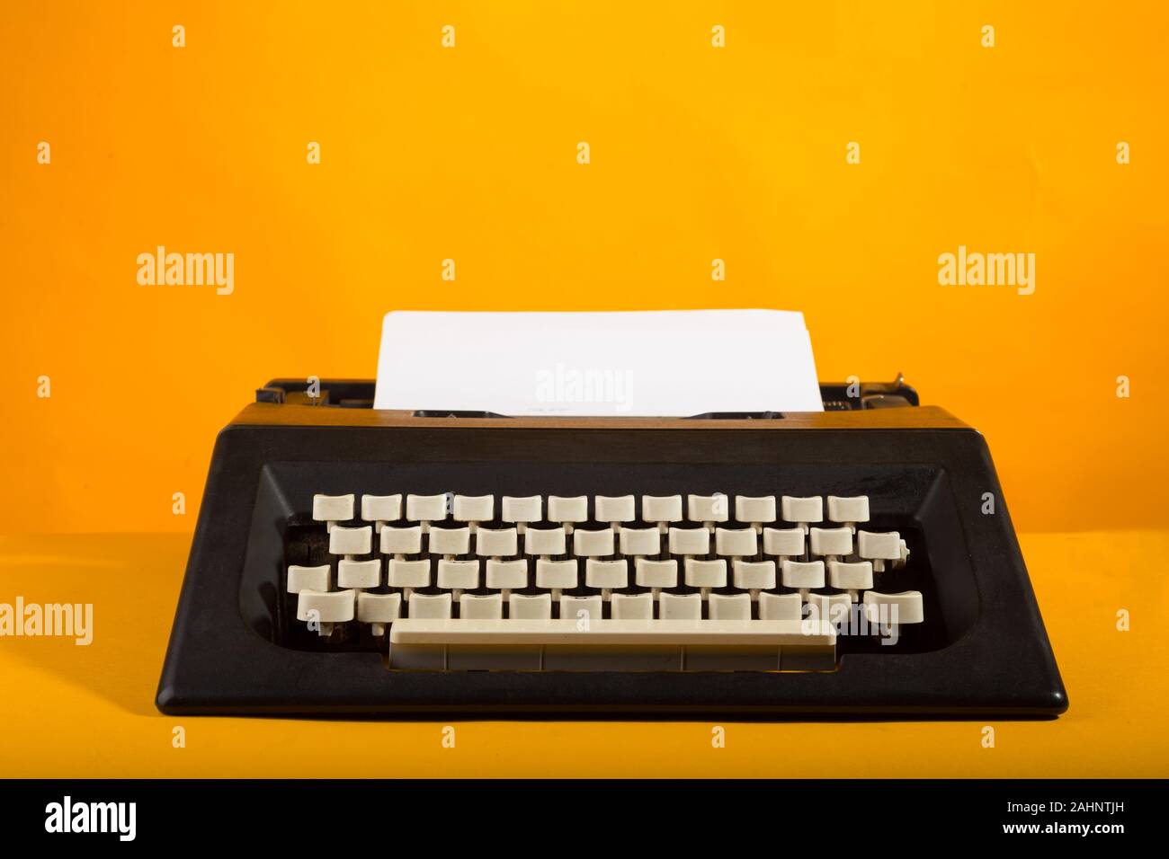 Black Typewriter isolated in yellow background Stock Photo - Alamy